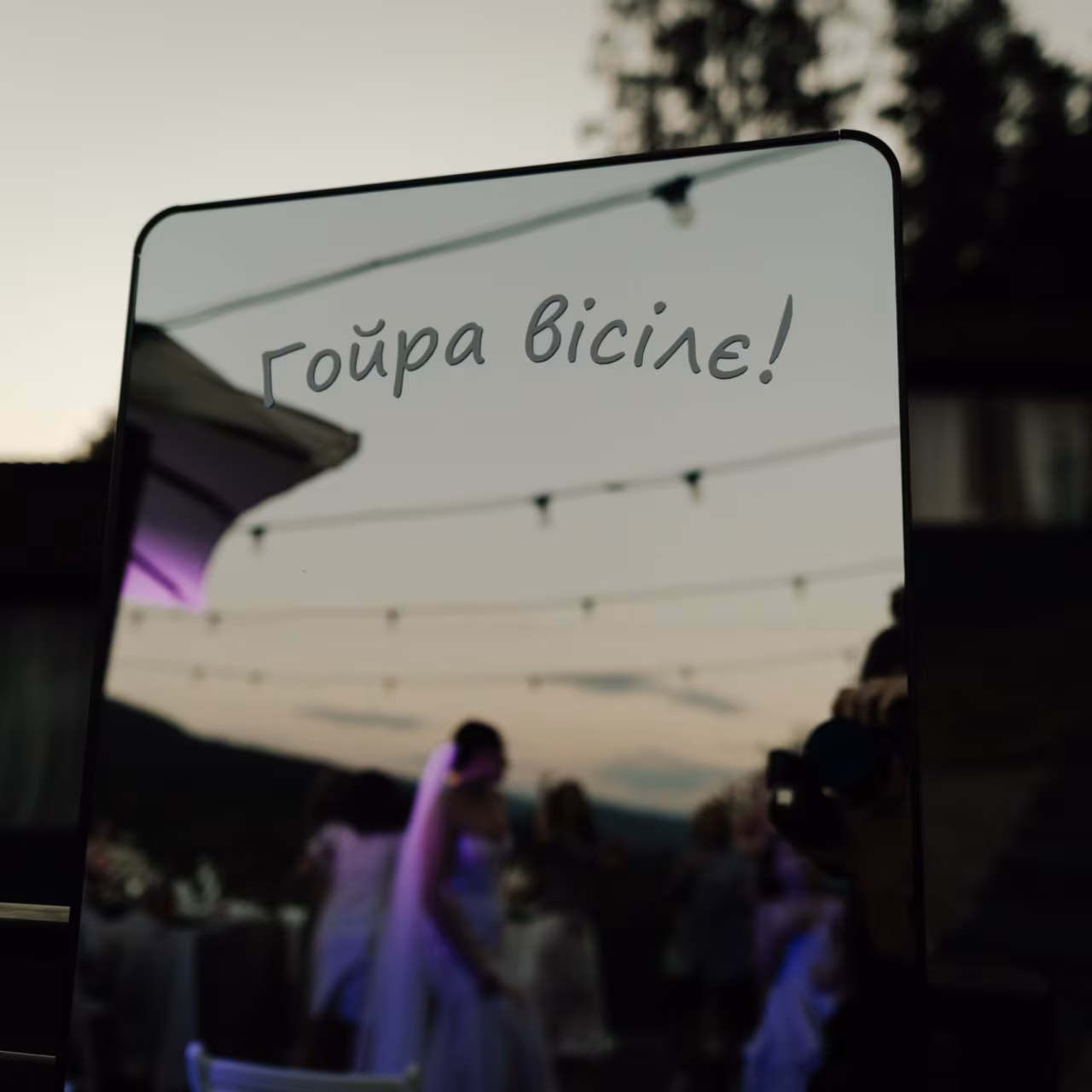 Дзеркало з написом «Гойра вісілє!», у якому відбивається весільна вечірка