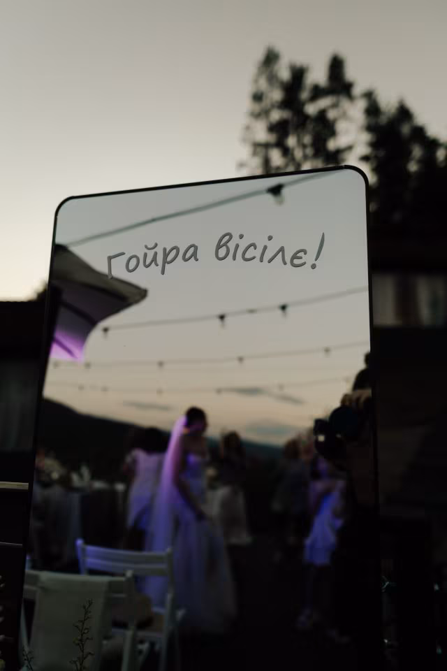 Дзеркало з написом «Гойра вісілє!», у якому відбивається весільна вечірка